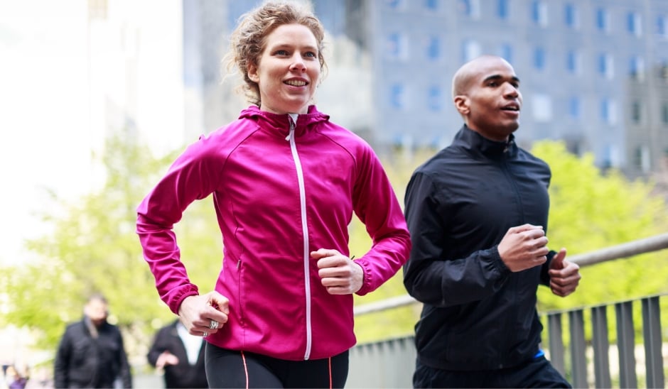 Two people running outside with trees in the background