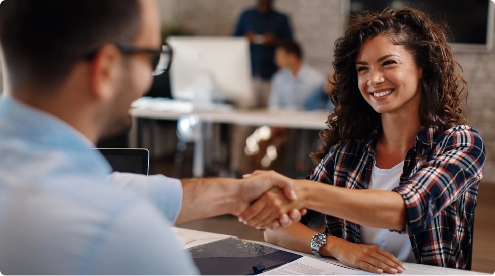 A woman and a man shaking hands across the table