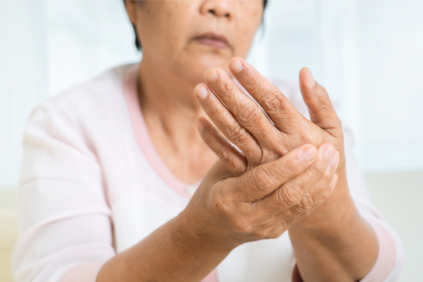 an elderly woman rubbing her hands due to arthritis pain
