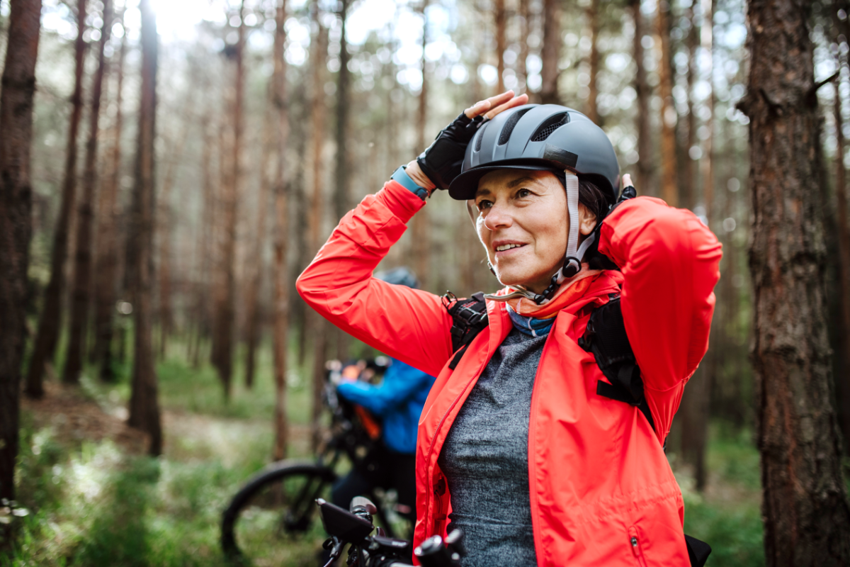 Woman in the forest adjusting her helmet. protect against concussion