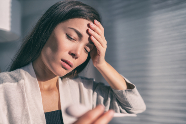 woman touching forehead checking temperature with thermometer.