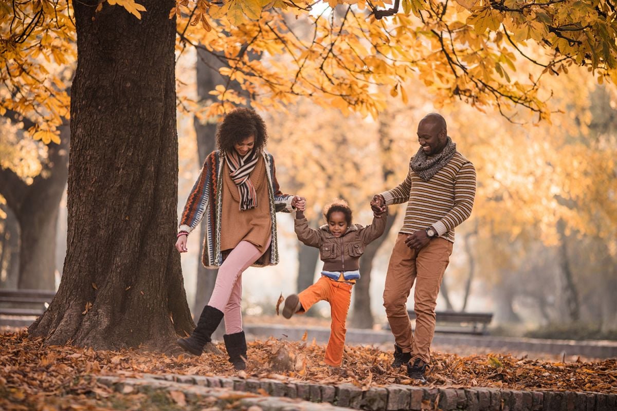 couple with a child moving among fall leaves