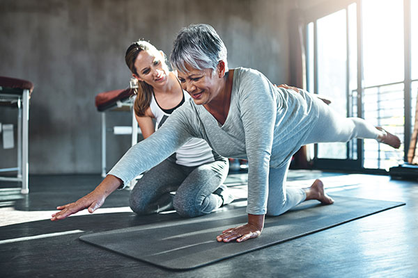 physiotherapist with a patient on a yoga mat exercising with cancer physiotherapist with a patient on a yoga mat exercising with cancer
