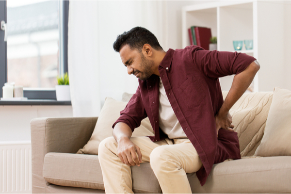 a man sitting on a couch suffering from back pain