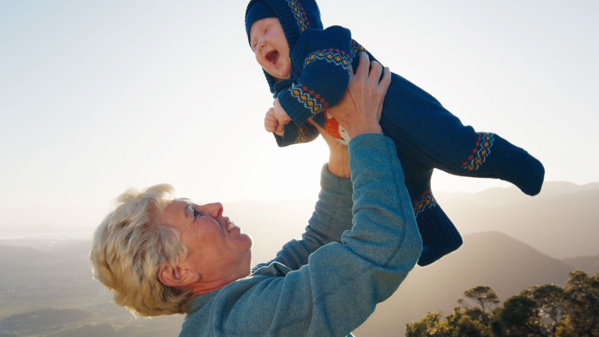 Grandmother holding toddler grandson up in the air