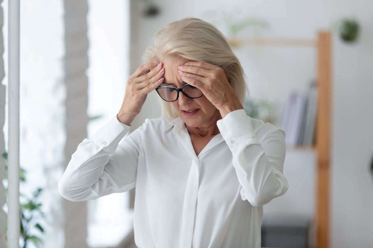 Woman with hands on head dizzy headache