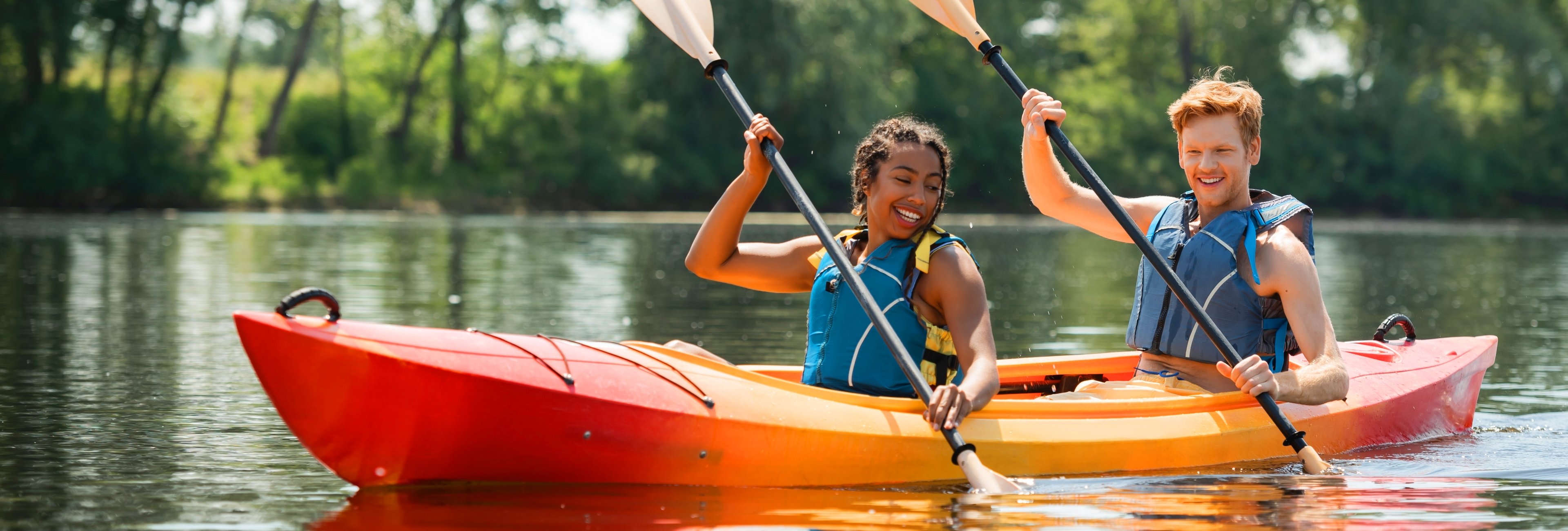 A young couple is enjoying kayaking together during the summer