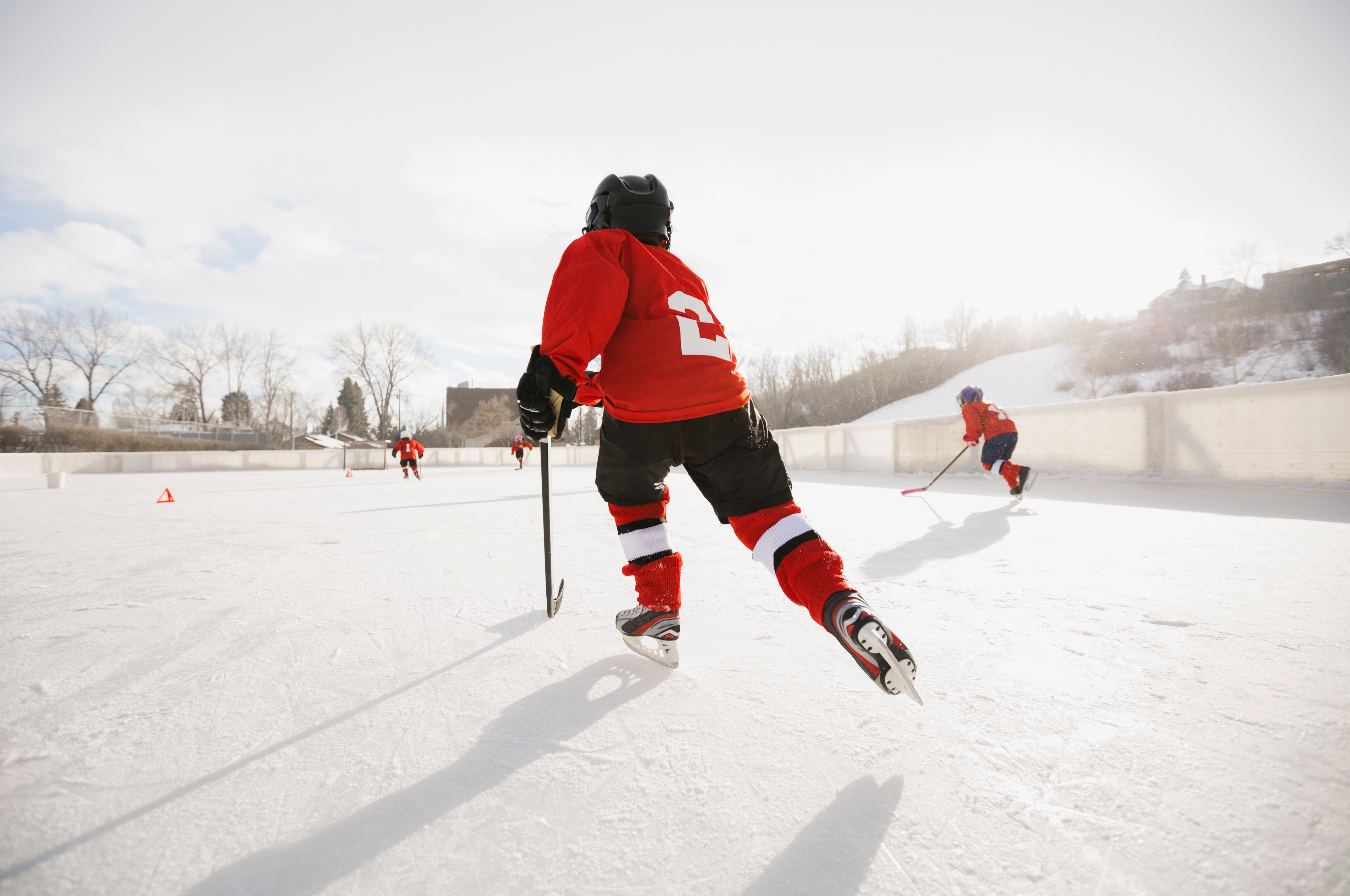 Two young adult ice hockey players in full gear competing for the puck, illustrating a contact sport with a risk of head injury and concussion."