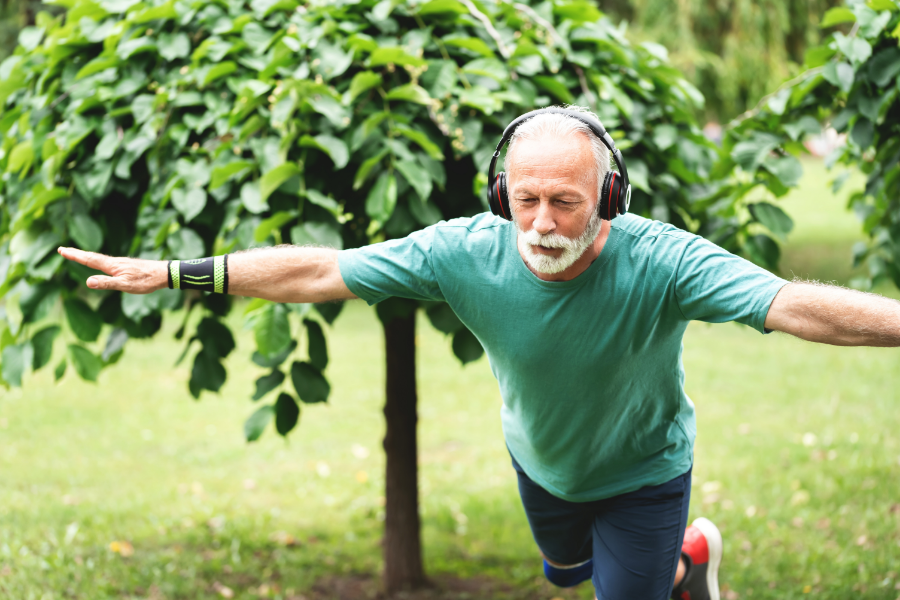 Older man balancing on one leg outdoors