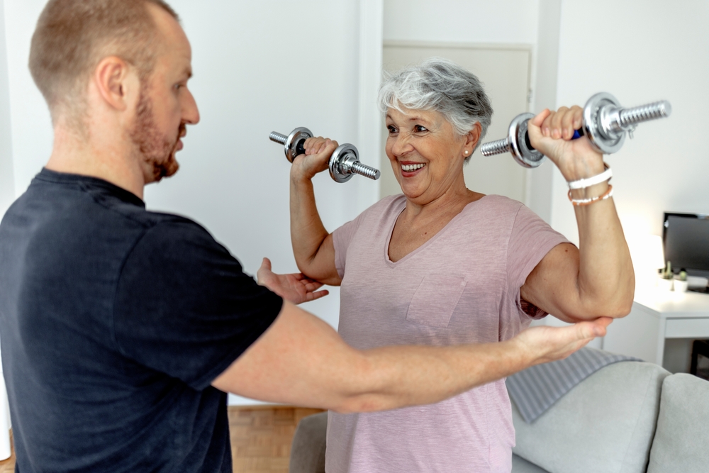 kinesiologist helping senior woman lift weights
