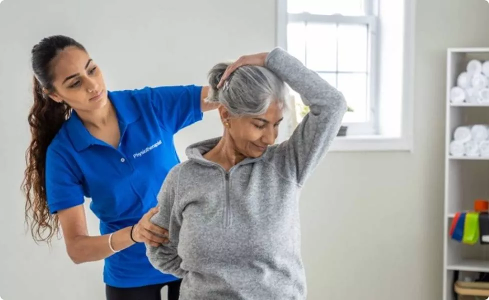 A student helping an elderly woman stretch