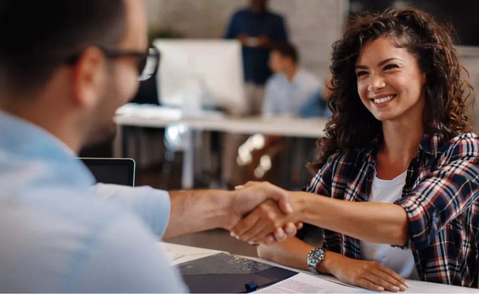 A woman and a man shaking hands across the table