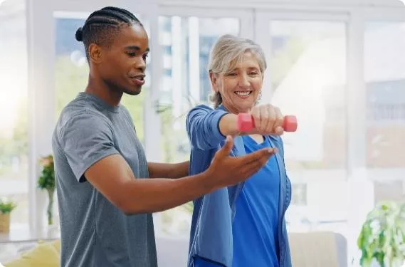 A young student helping an elderly woman lift weights