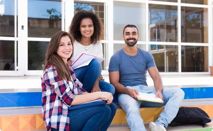 A couple students sitting outside smiling