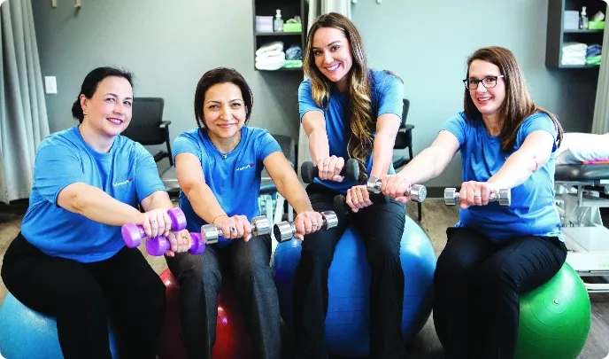 Lifemark employees stretching with weights on yoga balls