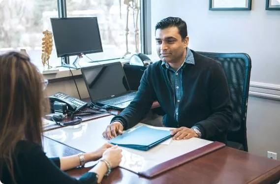 Gentleman behind a desk speaking to a woman