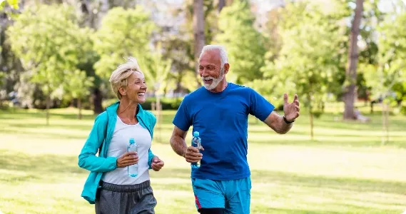 An elderly couple running in the park