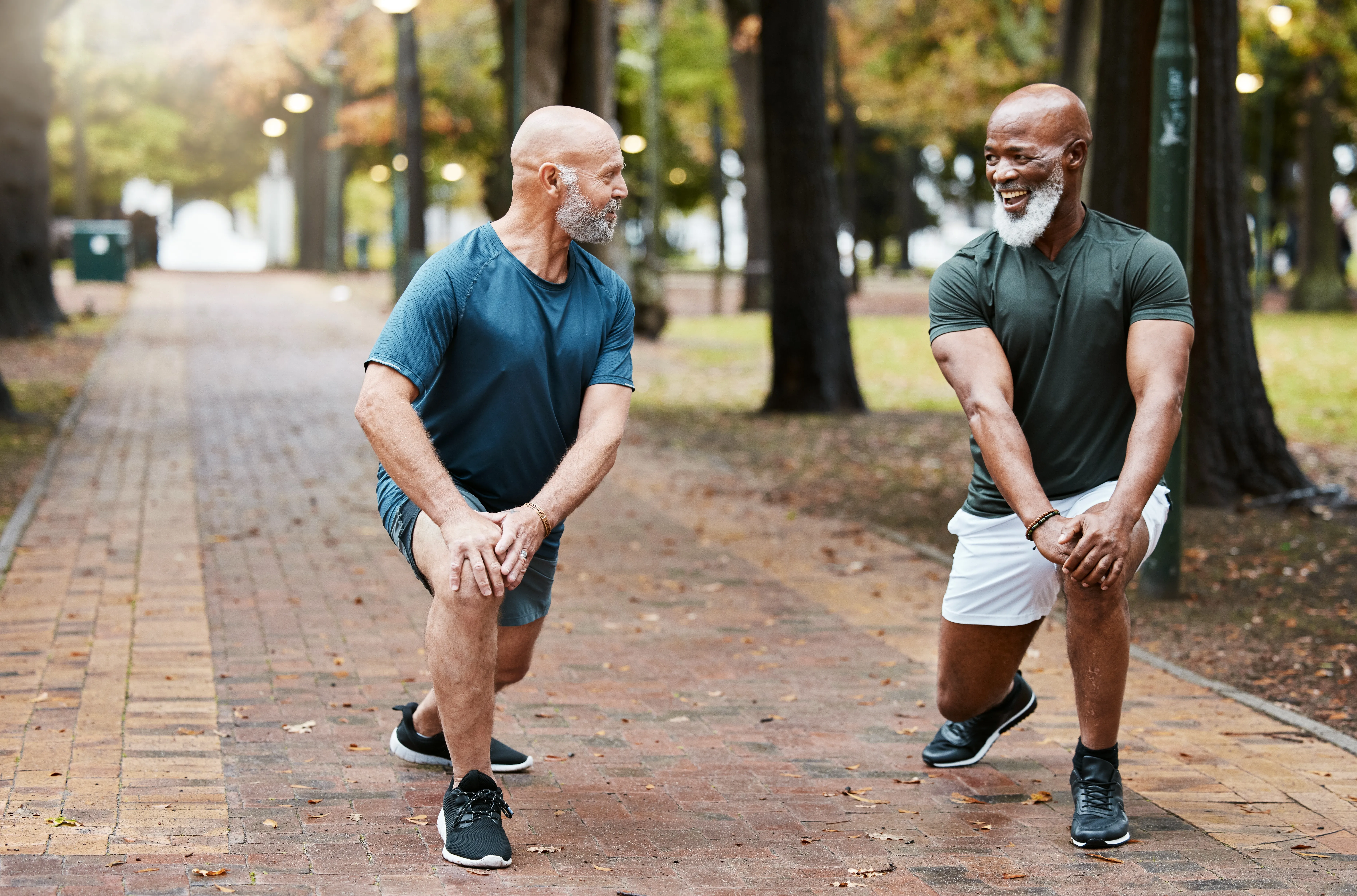 Two men lunging and performing knee exercises in a park for stronger knees